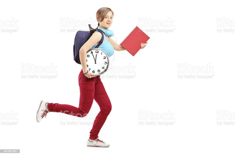 Full length portrait of a female student with clock late for class, isolated on white background